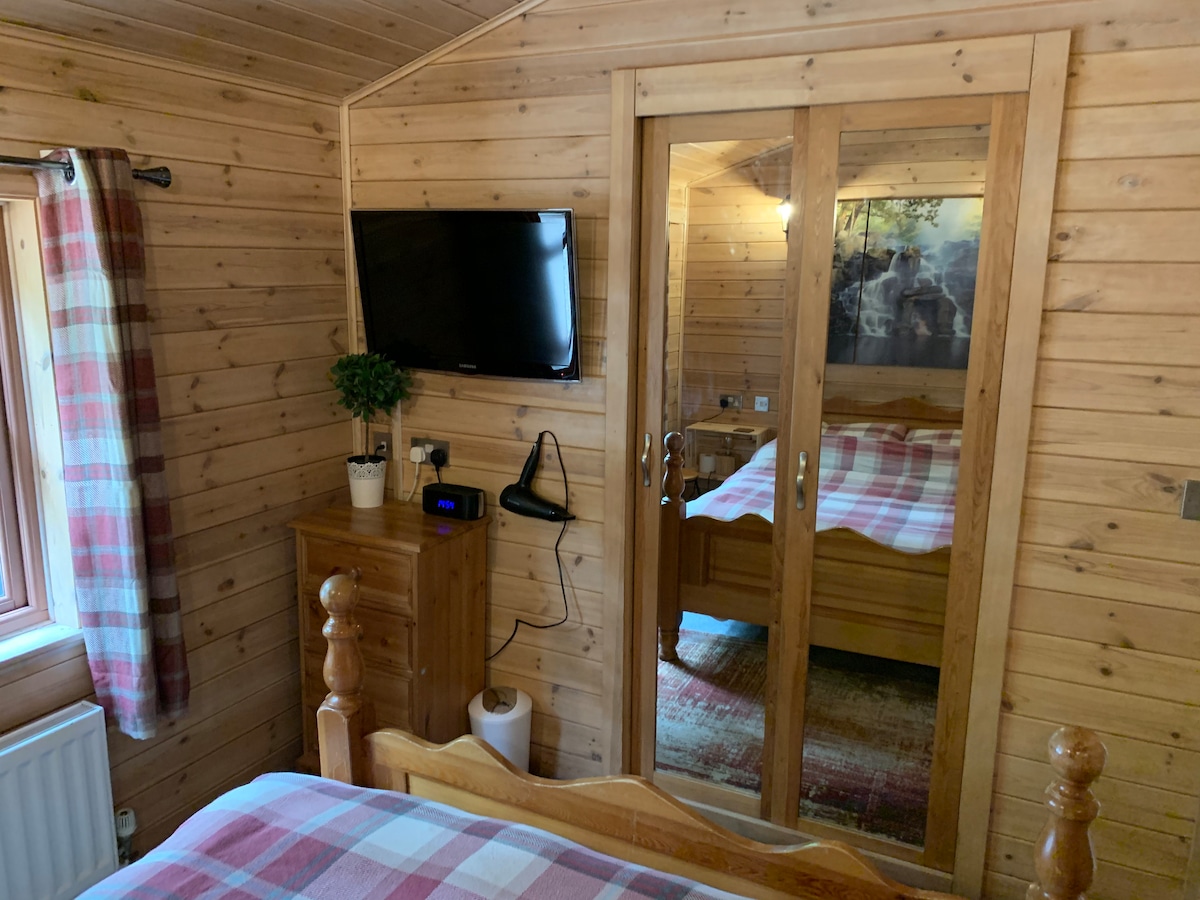 Double bedroom with wall-mounted TV, mirrored wardrobe and pine-panelled walls