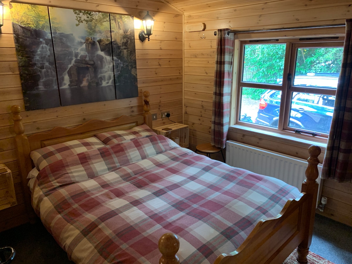Double bedroom with tartan bedding, waterfall wall art and woodland view