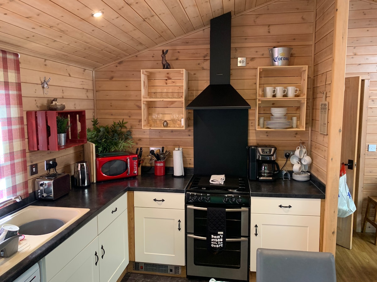 Kitchen with gas range, extractor hood, open shelving and red microwave
