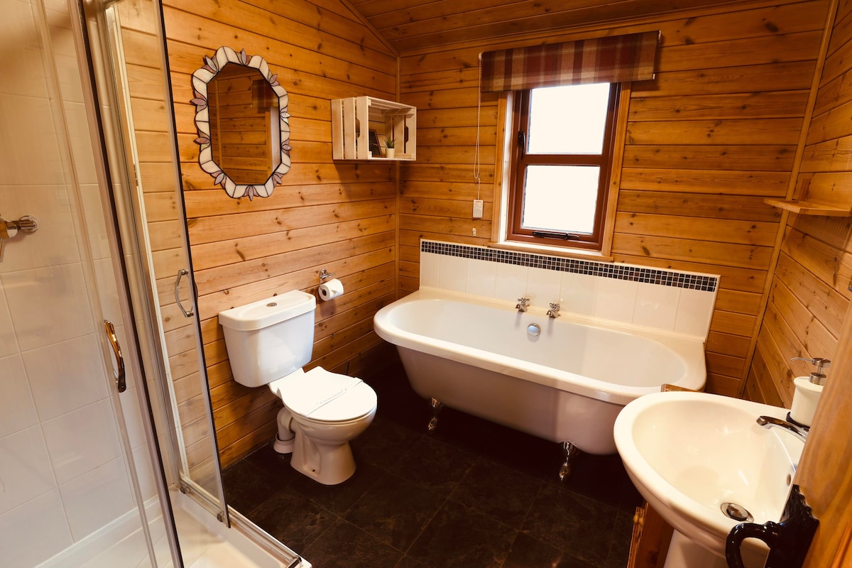 Bathroom with roll-top bath, walk-in shower, WC and pine-panelled walls