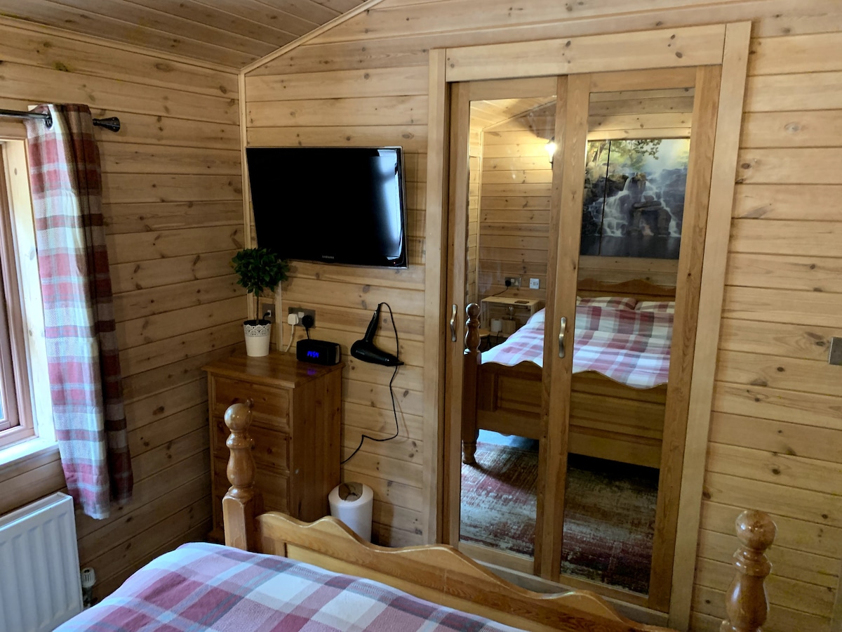 Main bedroom with wall-mounted TV, mirrored sliding wardrobe and tartan curtains