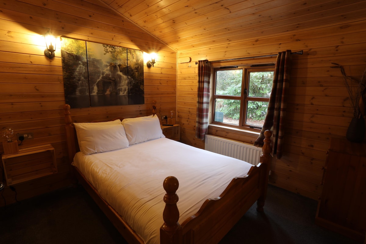Double bedroom with white linen, waterfall wall art and woodland window view