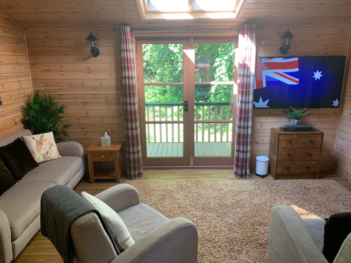 Bright living room with sofas, wall-mounted TV, skylight and doors to the deck