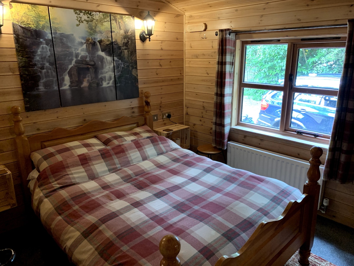 Double bedroom with tartan bedding, waterfall wall art and woodland view