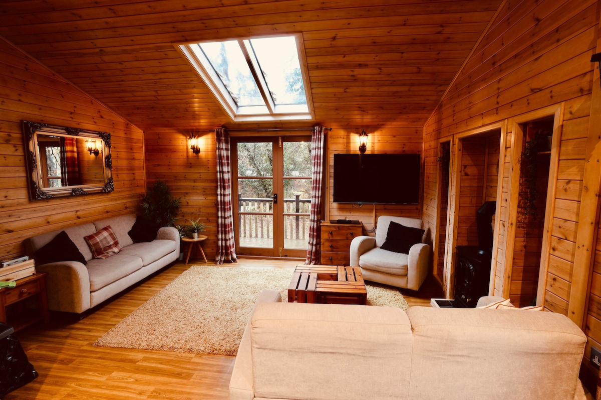 Living room with vaulted skylight, large wall-mounted TV and French doors to the deck